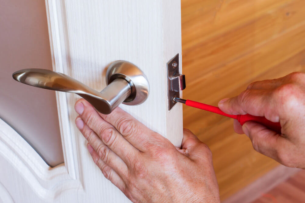 פורץ מנעולים מאמר | carpenter-repairs-front-door-lock-fastens-handle-with-screwdriver